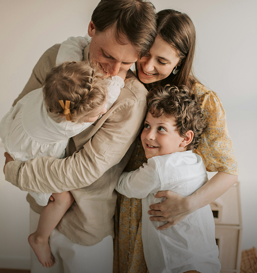 A family joyfully hugging together in their home, symbolizing love and support in a nurturing environment.