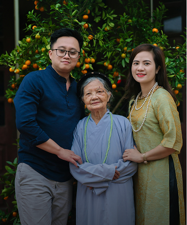 A man and woman stand beside an orange tree, surrounded by vibrant green leaves and ripe oranges.