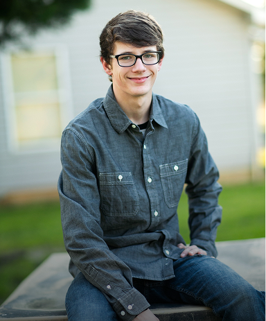 Young man with glasses sitting outdoors, representing teen therapy clients