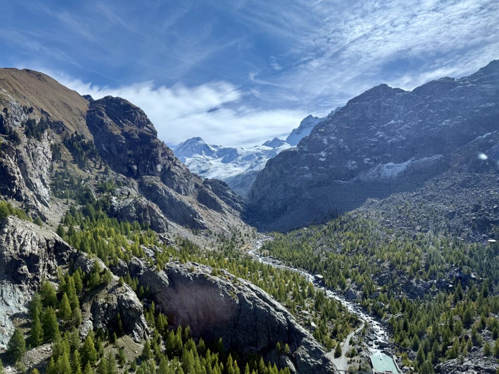 Mountain landscape with a river winding through the valley beneath a cloudy sky.