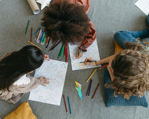 Children drawing and coloring together on the floor during a creative activity